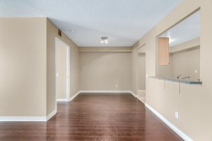 Empty room with beige walls and dark wooden floor.