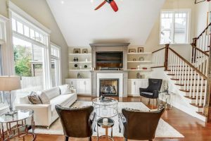 Bright living room with white sofas, fireplace, and dark leather chairs.