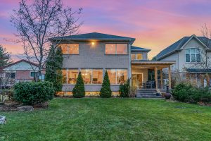 A two-story house at sunset with a well-kept lawn and shrubs.