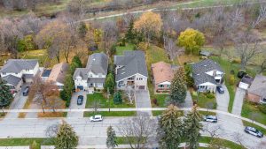 Aerial view of suburban houses lined along a street with autumn trees.