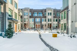 Snow-covered courtyard with apartment buildings and a clear footpath.