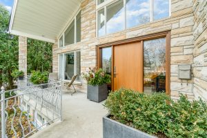 Modern patio with wooden sliding doors and outdoor seating area surrounded by greenery.