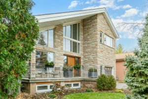 Modern house with large windows and stone facade.