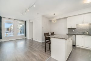 Bright modern kitchen and living space with hardwood floors and island seating.