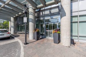 Entrance to a modern building with glass doors and concrete pillars.