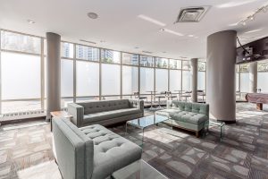 Modern office lounge with large windows and stylish seating.