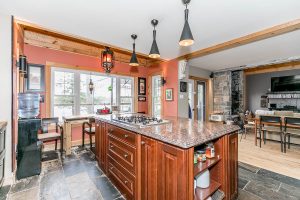 Spacious kitchen with a large island and bar seating overlooking a living area.