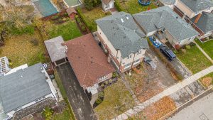 Aerial view of houses with yards and driveways in a suburban neighborhood.