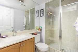Modern bathroom with glass shower and wooden vanity.