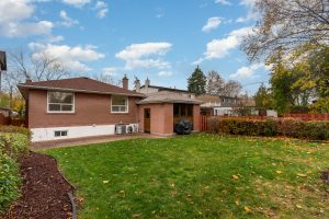 Spacious suburban home with large green lawn and mature trees.