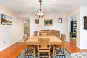 Cozy dining area with wooden table and chairs on patterned rug.
