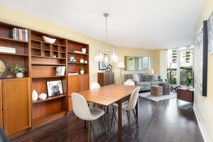 Bright, modern dining and living area with wooden furniture and large windows.