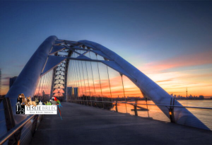 Modern bridge silhouetted against a vibrant sunset sky.