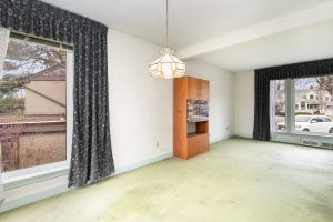 Bright empty room with large windows and green carpet.